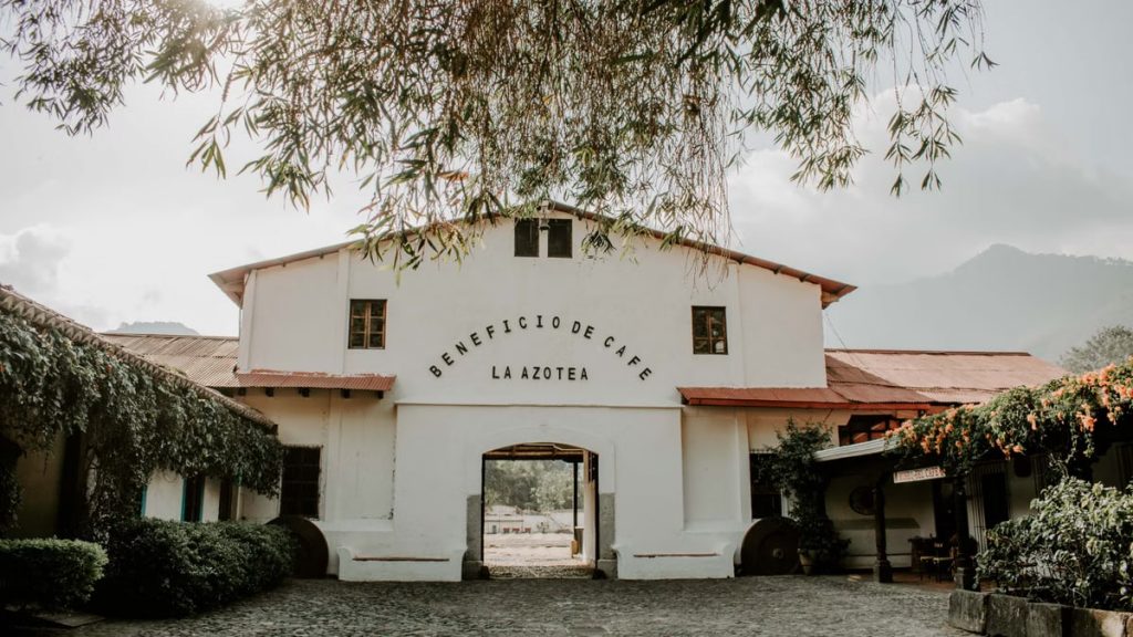 Charming historic building of Beneficio de Cafe La Azotea surrounded by lush greenery and cobblestones.